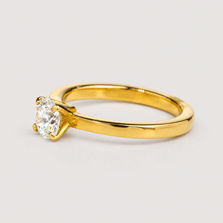 The 0.73ct Round Lab Diamond Solitaire Engagement Ring in 14k gold features a single round lab diamond in classic prongs—an elegant women's engagement ring set against a warm off-white studio background.