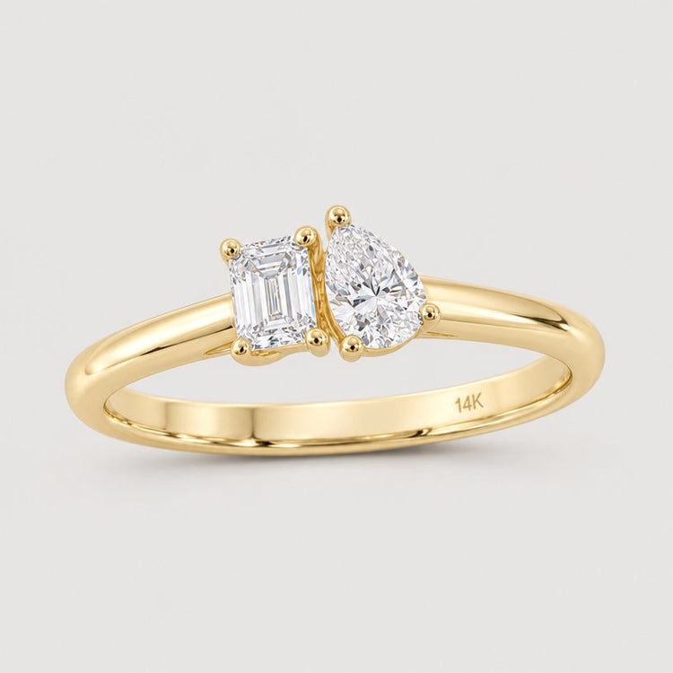The 1/2CTW 14k Yellow Gold 2-Stone Diamond Ring features natural emerald-cut and pear-shaped diamonds set side by side on a split shank band, marked with 14K inside.