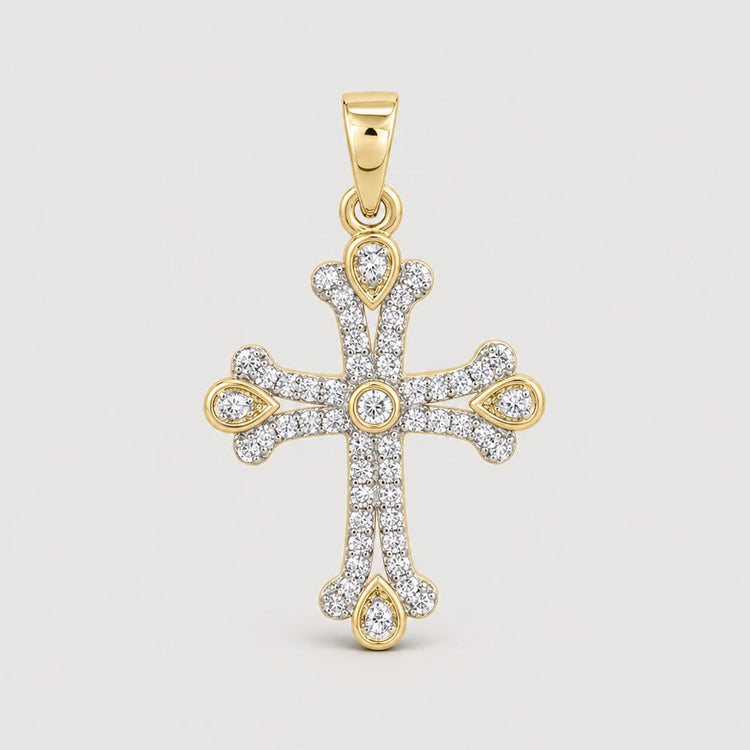 The 1/4CTW Diamond Cross Pendant in 10K Yellow Gold features small diamonds with rounded edges and teardrop-shaped gold accents—an elegant expression of faith, shown against a plain warm off-white studio background.