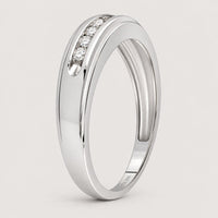 The 10k White Gold Round Diamond Wedding Band 1/4 Cttw features three small, round diamonds set in a smooth, slightly curved band, shown against a plain warm off-white studio background.
