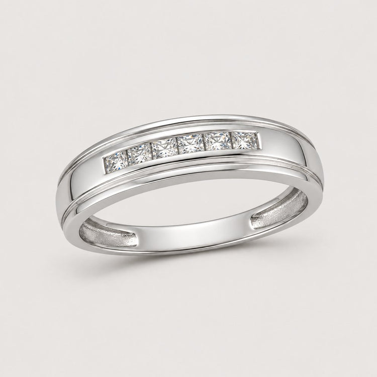 The 10k Gold Round Diamond Wedding Band – 1/12 Cttw features a sleek polished band set with sparkling round diamonds in a row, displayed against a plain warm off-white studio background.
