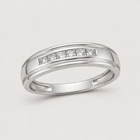 The 10k Gold Round Diamond Wedding Band – 1/12 Cttw features a sleek polished band set with sparkling round diamonds in a row, displayed against a plain warm off-white studio background.