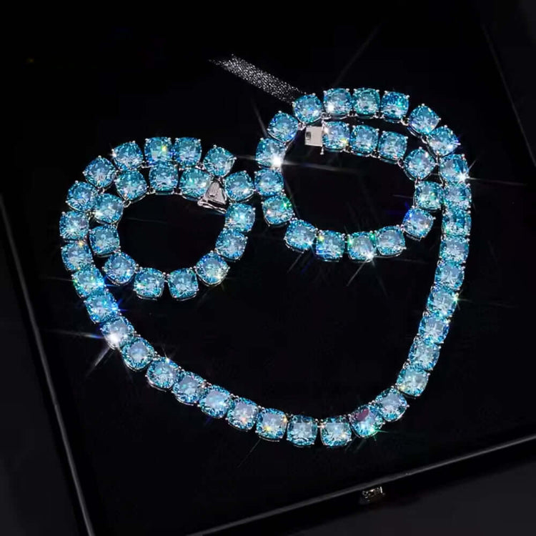 The Blue Moissanite Tennis Chain - 10mm is a sparkling jewelry set with a silver necklace and bracelet featuring square-cut blue stones, displayed on a black background reflecting light.