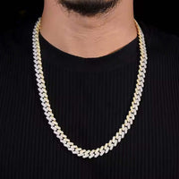 A man wears the Moissanite Cuban Link Chain - 10mm, a thick gold and silver necklace, over a ribbed black shirt, shown from shoulders to chin against a dark background.