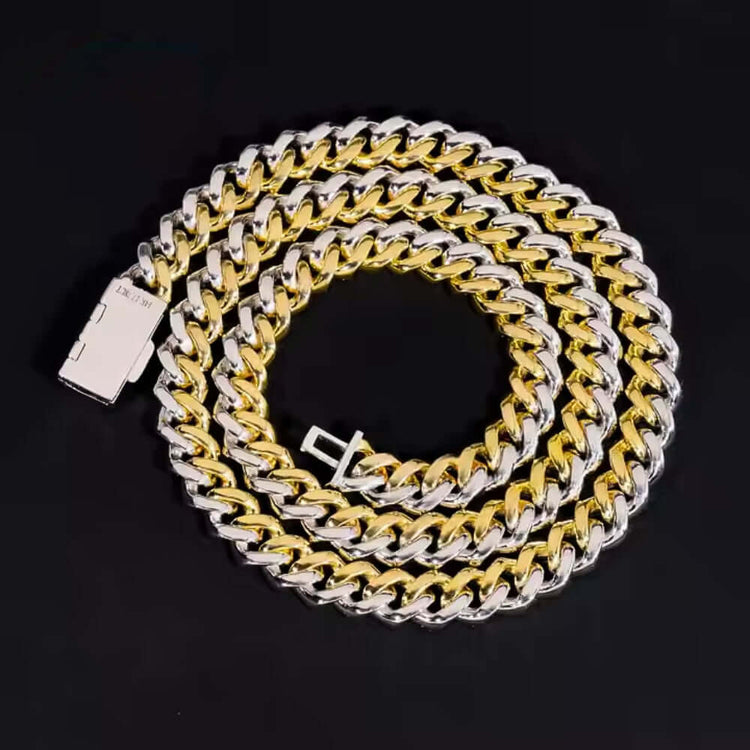 The Moissanite Cuban Link Chain - 10mm features interlocking gold and 925 sterling silver links, coiled in a spiral on a black background with the clasp visible at one end.
