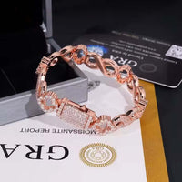 The Infinity Clover Moissanite Bracelet - 11mm features rose gold, a rectangular diamond-encrusted centerpiece, and intricate chain links, shown near an open box and luxury brand documents.