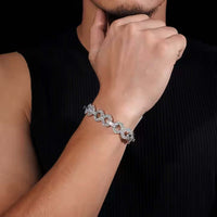 A person in a sleeveless black shirt showcases the Silver Moissanite Infinity Bracelet - 13mm on their wrist, thoughtfully resting their hand on their chin against a black background.