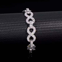 The Silver Moissanite Infinity Bracelet - 13mm features sparkling, interlocking infinity links encrusted with clear gemstones, beautifully displayed on a textured black surface.