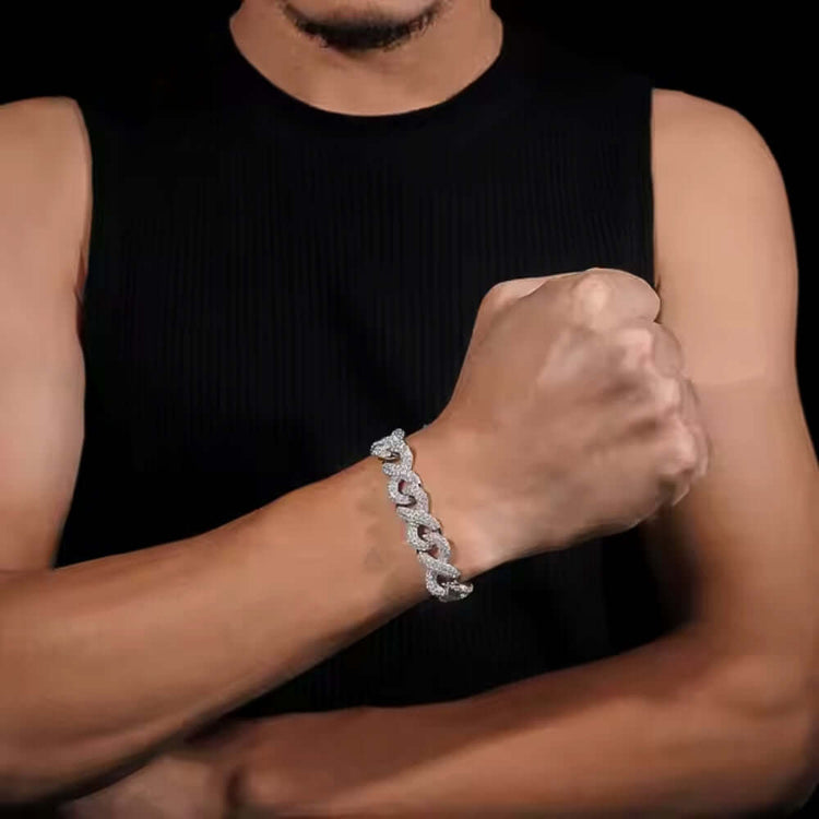 A person in a sleeveless black top shows off a chunky Silver Moissanite Infinity Link Chain -13MM bracelet on their wrist, fist raised against a dark background.