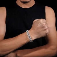 A person in a sleeveless black top shows off a chunky Silver Moissanite Infinity Link Chain -13MM bracelet on their wrist, fist raised against a dark background.