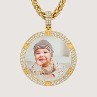 The 14K Gold Diamond-Accented Round Picture Pendant displays a round photo of a smiling baby in a striped hat and light clothes, set in 14K gold with sparkling diamond accents.