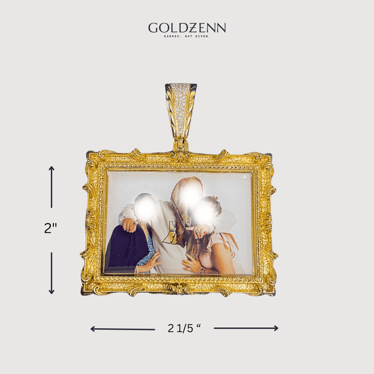 The 14K Gold Diamond Bail Big Frame Picture Pendant, featuring ornate edges and a rectangular shape, displays a photo of three people. Black arrows show its size: 2" tall by 2.15" wide. The “GOLDZENN” logo is above this elegant pendant.