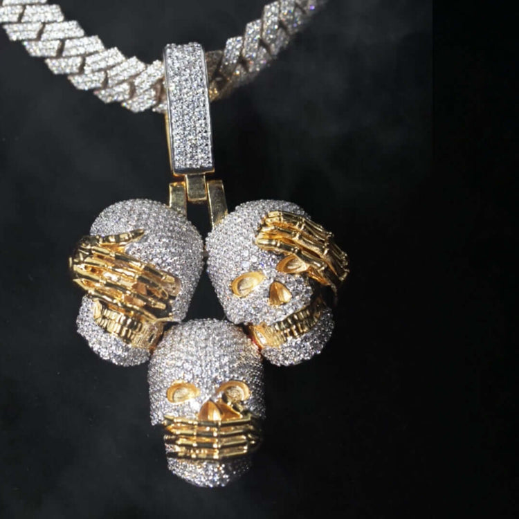 The 14k Hear No Evil, See No Evil, Speak No Evil Pendant features three silver skulls with 14K gold hands covering mouth, eyes, and ears, symbolizing the iconic “see no evil, hear no evil, speak no evil” motif.