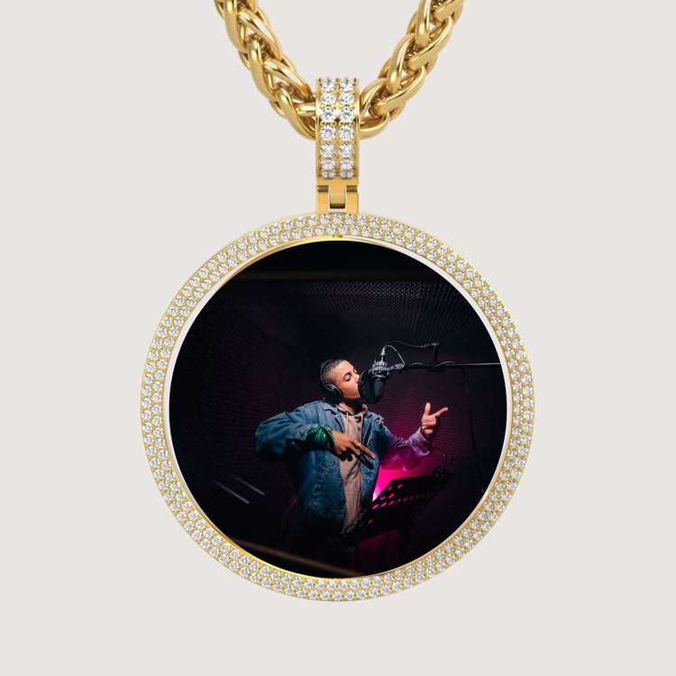 The 14K Gold Double Diamond Halo Round Picture Pendant features shimmering diamonds and displays a studio photo of someone rapping or singing into a mic, headphones on, in a denim jacket under purple lights.