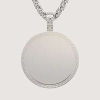 The 14K Gold Greek Key Round Picture Pendant features a subtle geometric border inspired by the Greek Key pattern and hangs from a thick, twisted gold chain with a small gemstone set above the pendant.