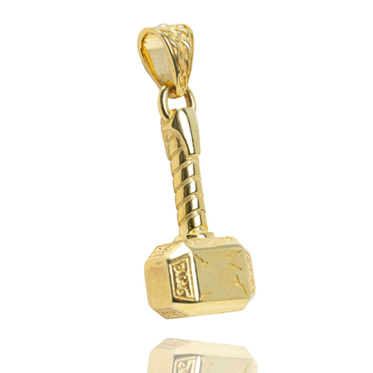 The 14k Solid Gold Hammer Pendant showcases detailed handle and head designs, photographed on a white background with a subtle reflection—highlighting its exquisite craftsmanship.