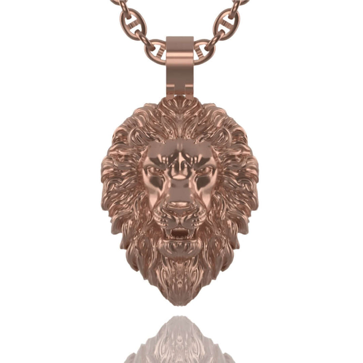 A close-up of the 14k Gold Lion Head Pendant on a chain, showing its detailed fur and facial features against a white background. The polished gold surface of the pendant reflects light beneath it.