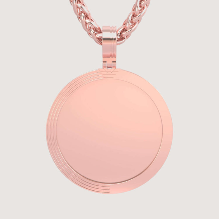 The 14K Gold Modern Grooved Round Picture Pendant in rose gold features a subtle grooved edge and hangs from a matching twisted chain, elegantly displayed against a light background.