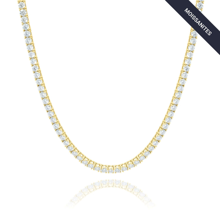 The Tennis Chain - 14K Gold Moissanite features a single row of round white moissanite stones on a white background. A dark diagonal MOISSANITES label in the top right corner highlights this elegant, ethical luxury piece.