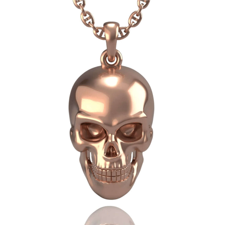 The 14k Gold Skull Pendant features a shiny, metallic human skull design and hangs from a matching chain necklace, displayed against a white background.