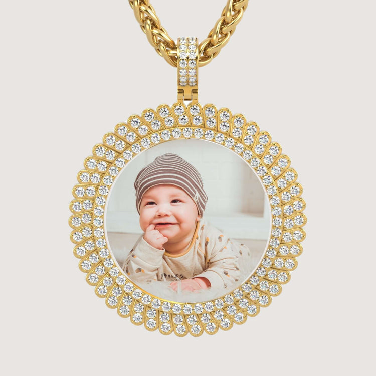 The 14K Gold Sunburst Diamond Round Picture Pendant showcases a photo of a smiling baby in a striped hat and patterned outfit, accented with sparkling diamonds.