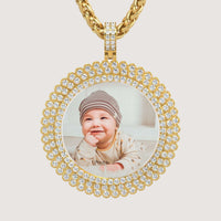 The 14K Gold Sunburst Diamond Round Picture Pendant showcases a photo of a smiling baby in a striped hat and patterned outfit, accented with sparkling diamonds.