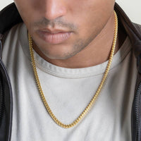 A man wears a white t-shirt, black jacket, and a Franco Chain - 3mm-3.5mm 14k Gold Bonded necklace. The image highlights his lower face, neck, and upper chest.