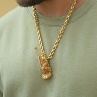 A person wearing a light green shirt and a thick gold rope chain necklace with the Saint Christopher Pendant - 14k Gold, featuring a detailed design of the robed figure holding a staff.