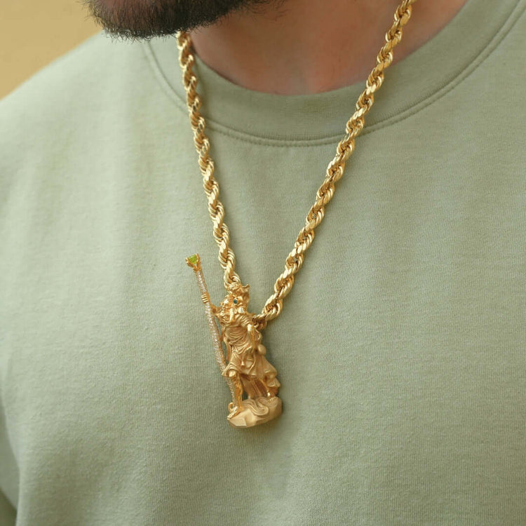 A person wearing a light green shirt and a thick gold rope chain necklace with the Saint Christopher Pendant - 14k Gold, featuring a detailed design of the robed figure holding a staff.