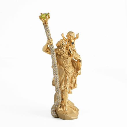 The Saint Christopher Pendant - 14k Gold is a detailed, ornate golden pendant featuring a robed figure holding a jewel-topped staff with blue and green gemstone accents, echoing the intricate design of religious jewelry.