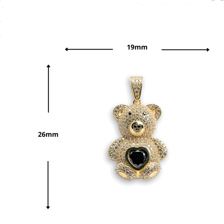 The 14k Yellow Gold Teddy Bear Pendant showcases a black heart gem on its belly and clear stone accents. Measuring 26mm tall by 19mm wide, it is displayed against a white background with measurement arrows.