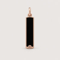 The 14k Gold Black Enamel Tag Pendant features a rectangular black enamel design accented with rose gold edges and finished with a small circular detail at the bottom, all set against a minimalist light background—an elegant piece crafted to elevate any look.