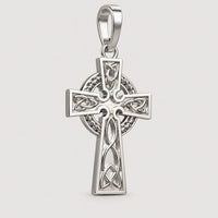 A 14k gold Celtic cross pendant featuring intricate knotwork and a circular motif behind the crossbar, displayed on a warm off-white studio background with a subtle contact shadow below.