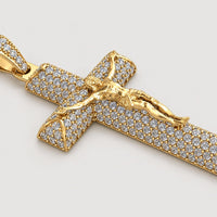 The 14K Gold Diamond Crucifix Pendant features a detailed figure of Jesus on the cross, encrusted with small diamonds and displayed against a plain warm off-white studio background.