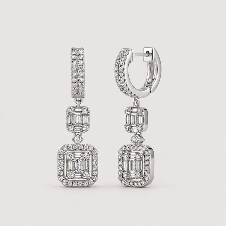 The 1 Cttw 14k White Gold Baguette Diamond Dangle Earrings feature rectangular baguette diamond clusters framed by smaller diamonds, suspended from diamond-studded hoops against a light gray background.