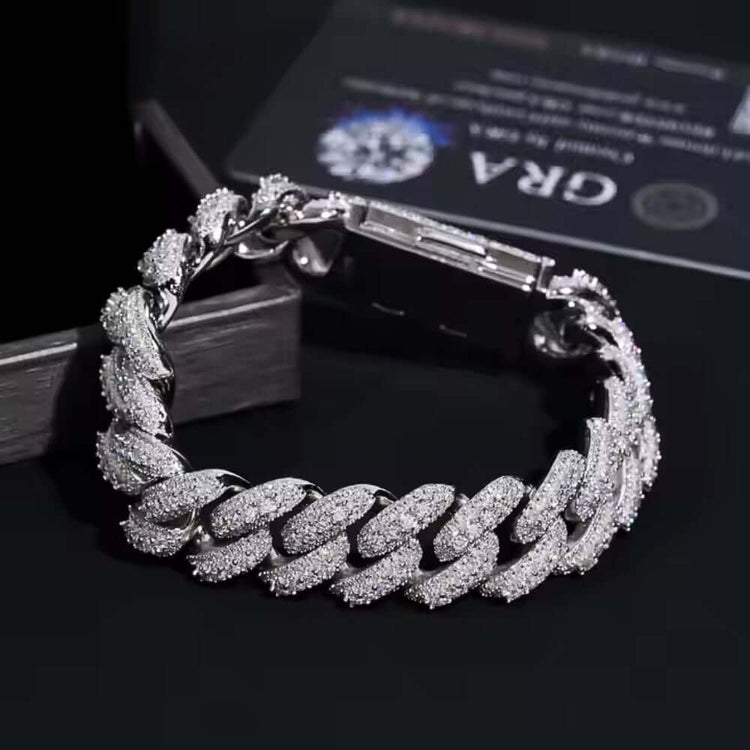 A close-up of the Silver Moissanite Cuban Link Bracelet - 16mm, crafted in 925 sterling silver and set with sparkling moissanites, displayed on a black surface with a certificate card partially visible in the background.