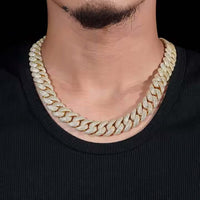A person wears the Yellow Iced Out Moissanite Cuban Link Chain - 16mm over a black ribbed shirt, with focus on the neck and chest area.
