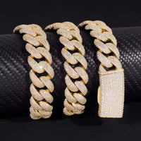 Three gold Cuban link bracelets, encrusted with small diamonds and featuring a large rectangular clasp, rest on a black cylinder—each reflecting the luxurious brilliance of the Yellow Iced Out Moissanite Cuban Link Chain - 16mm.