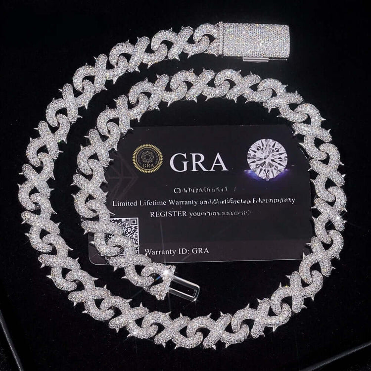 The Silver Moissanite Infinity Necklace - 16mm, crafted from 925 sterling silver and moissanite, is displayed coiled on a black GRA card featuring a diamond graphic and warranty info, with a pen placed beside it.