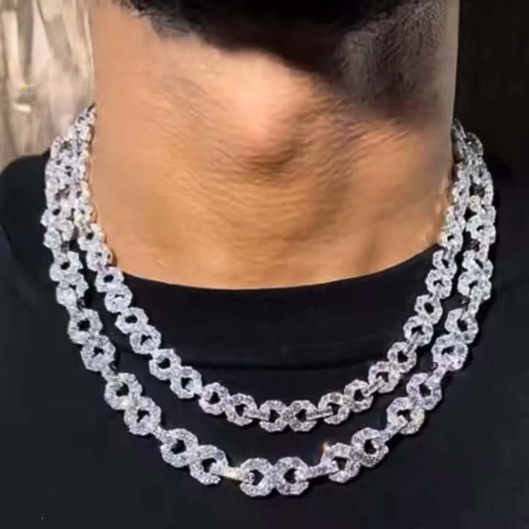 A close-up of a person wearing a black shirt and two thick Silver Moissanite Infinity Necklaces (16mm) crafted from 925 sterling silver, each encrusted with sparkling moissanite diamonds around their neck.
