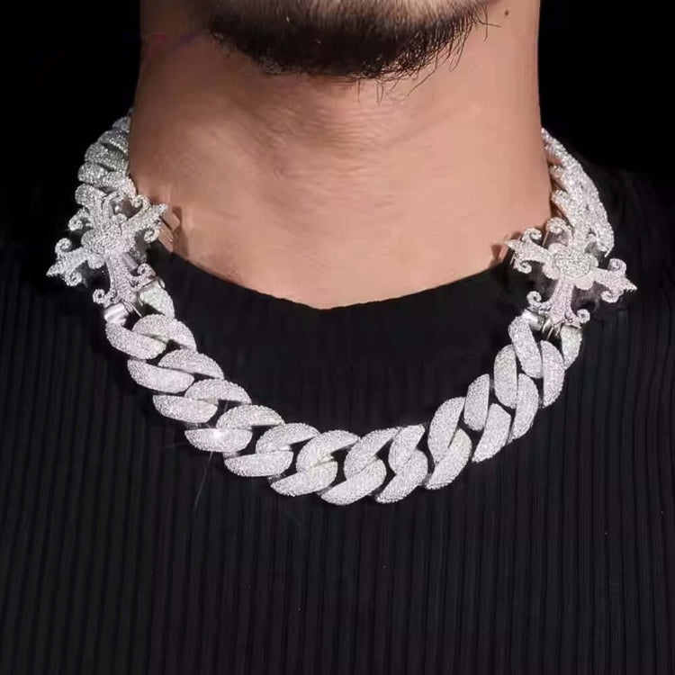 A close-up of a person wearing the Moissanite Cross Cuban Link Chain - 18mm, featuring VVS moissanite cross pendants, over a black ribbed shirt.