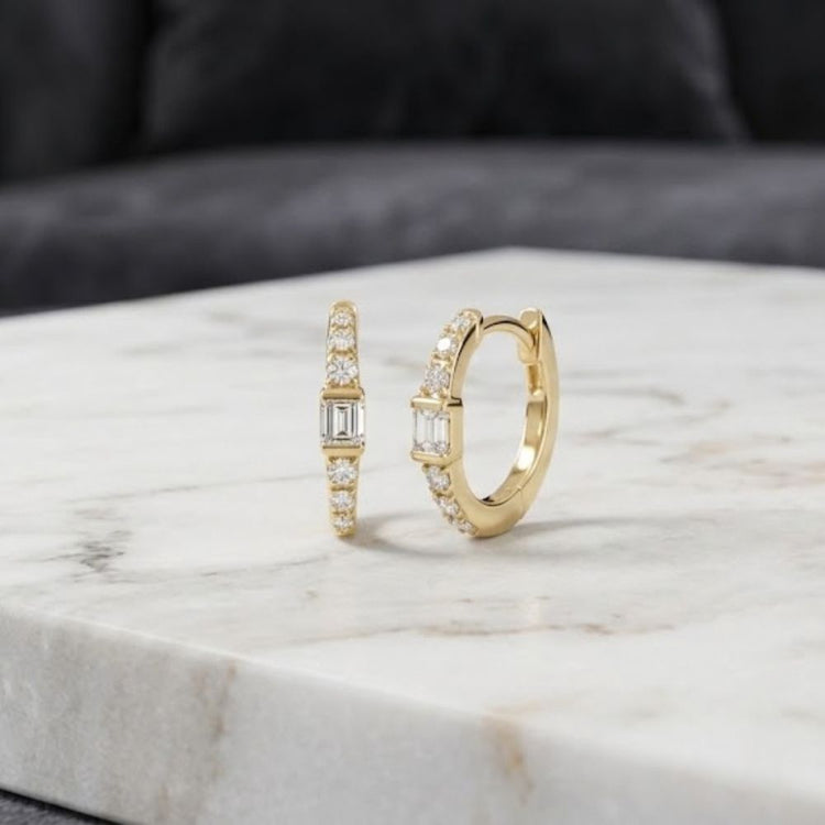 1/8CTW Natural Diamond Hoop Earrings 10K Gold featuring a central baguette-cut natural diamond flanked by smaller round diamonds in 10K yellow gold.