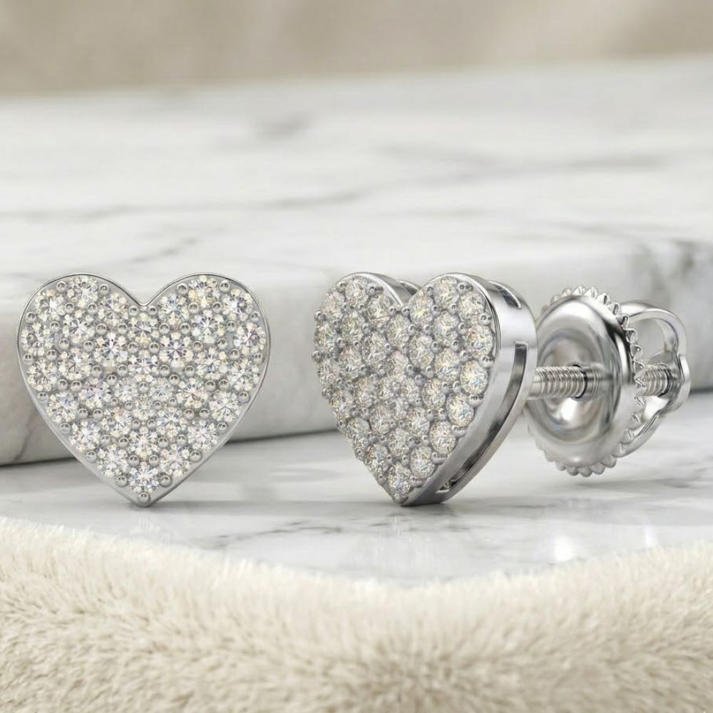 A close-up of 1/3CTW Natural Diamond Heart Earrings in sterling silver, adorned with sparkling diamonds, displayed on a soft beige fabric.