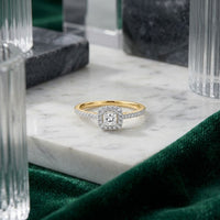 Showcased on a marble surface with glass and marble accents and green fabric, the 10k Gold Princess Diamond Halo Engagement Ring features a dazzling princess-cut diamond surrounded by a square halo of sparkling diamonds. This refined design adds timeless sophistication to any bridal engagement ring collection.