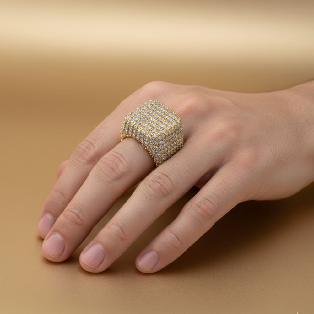 A hand showcases the Square Pavé Diamond Ring – 18 CT Gold Statement, featuring many sparkling diamonds, against a smooth light brown background.