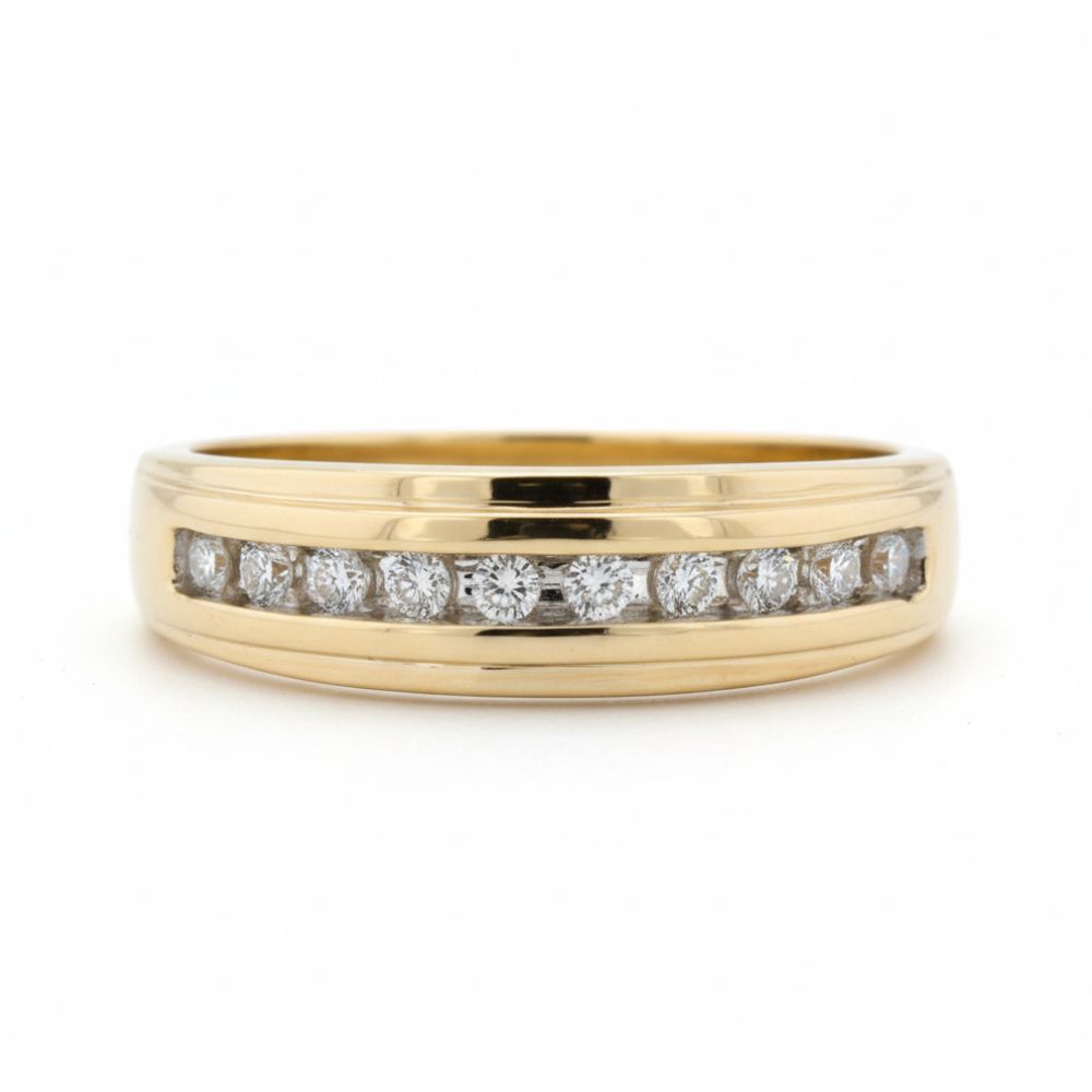 The 10k Yellow Gold Diamond Channel-Set Wedding Band 1/5 Ctw showcases a row of round white diamonds in a sleek channel setting on yellow gold, presented against a plain white background.