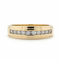 The 10k Yellow Gold Diamond Channel-Set Wedding Band 1/5 Ctw showcases a row of round white diamonds in a sleek channel setting on yellow gold, presented against a plain white background.