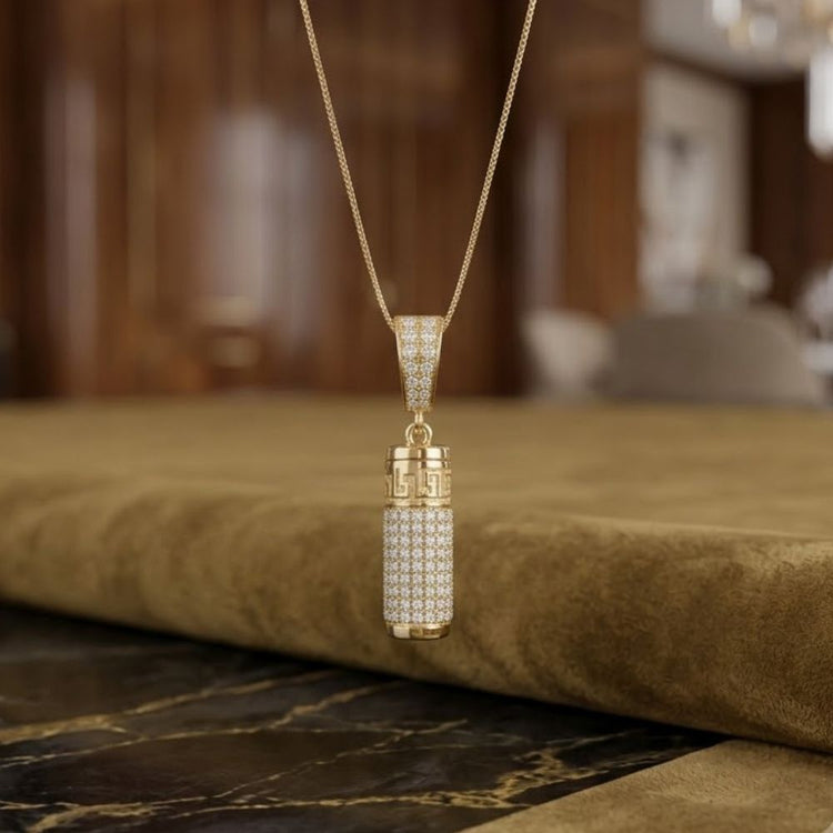 The 10K Gold Diamond Urn Cylinder Pendant 1 CTTW features a diamond-encrusted cylindrical design, elegantly displayed on a suede-like surface with a softly blurred, refined interior background.
