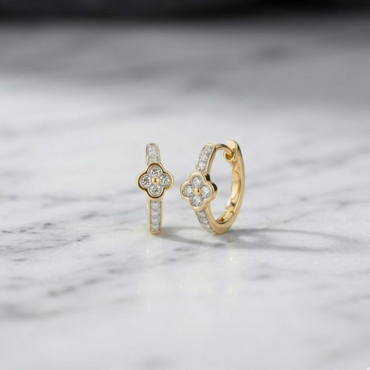 The 1/10 CTW Natural Diamond Clover Hoop Earrings showcase a charming clover-shaped design with sparkling diamond accents, elegantly displayed on a white marble surface.