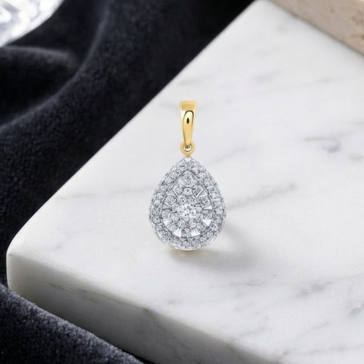 The 14K Gold 1/2 CTW Diamond Pear Pendant, showcasing a teardrop-shaped natural diamond with a gold bail, rests on a white marble surface surrounded by black textured fabric.